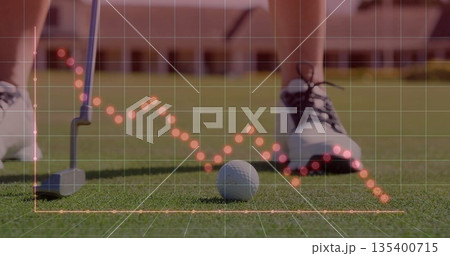 Resting golf ball showing orange dotted grid overlay near putter head, golf shoes on putting green 135400715