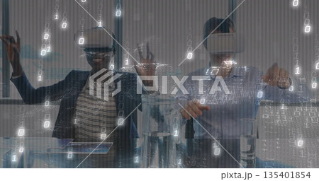 Two colleagues wearing blazers and VR headsets interacting in office meeting room, with tablet Two colleagues wearing blazers and VR headsets interacting in office meeting room, with tablet 135401854
