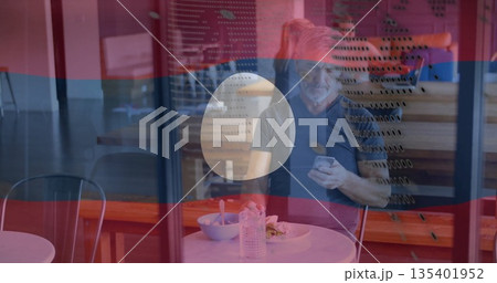 Sitting mature man eating meal at coffee shop behind perforated glass, with bowl and water bottle Sitting mature man eating meal at coffee shop behind perforated glass, with bowl and water bottle 135401952
