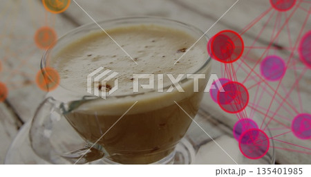 Displaying clear glass coffee cup resting on wooden tabletop, with network graphic nodes 135401985