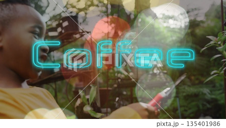 Trimming boy wearing yellow shirt in garden with pruning shears, neon-blue Coffee text, copy space 135401986