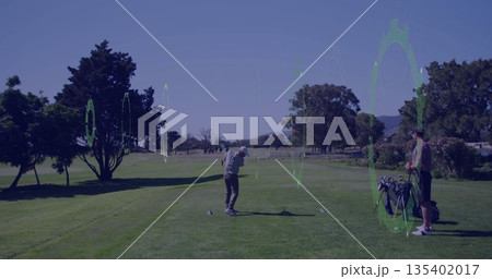 Swinging club by golfer wearing polo shirt hitting ball on tee on fairway, with golf bag 135402017
