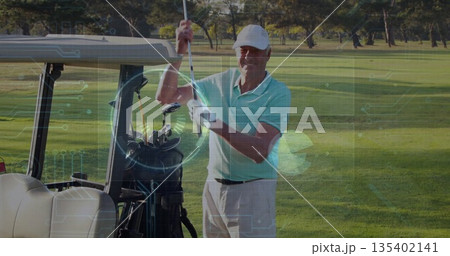 Holding golf club, senior golfer wearing polo shirt, cap preparing swing on fairway, with cart, bag Holding golf club, senior golfer wearing polo shirt, cap preparing swing on fairway, with cart, bag 135402141