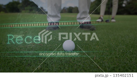 Sitting white dimpled golf ball on trimmed putting green, with spiked shoes and encrypted overlay 135402151