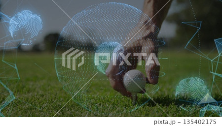 Sportswear-clad male hand placing white golf ball onto wooden tee on fairway with digital spheres 135402175