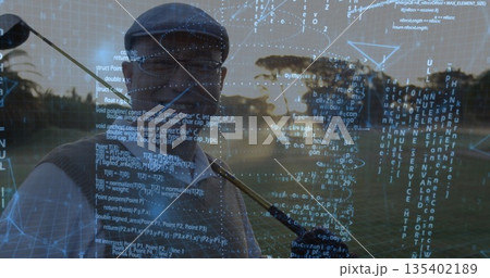 Chinese golfer shouldering golf club in flat cap at course sunset, with digital code overlay 135402189