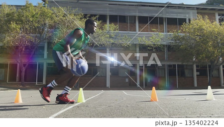 Dribbling man in green top guiding blue basketball around cones on outdoor court, copy space Dribbling man in green top guiding blue basketball around cones on outdoor court, copy space 135402224