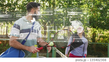 Tennis duo trading ball at net on outdoor court, with rackets, bag and data overlays 135402308