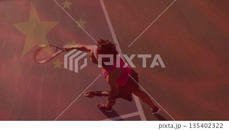 Swinging female tennis player hitting ball with racket on red hard court with lines, star overlay 135402322