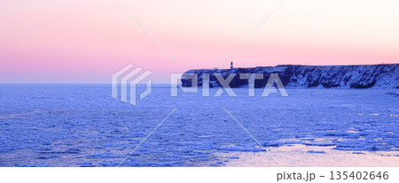 朝焼けの中に浮かぶ流氷が接岸した真冬の北海道網走市能取岬 朝焼けの中に浮かぶ流氷が接岸した真冬の北海道網走市能取岬 135402646