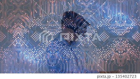 Standing man wearing suit and tie behind translucent panel in office, with glowing circuit pattern 135402723