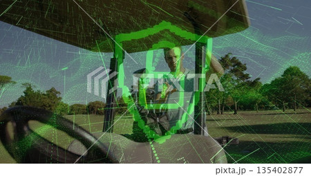 Standing adult male golfer holding smartphone on golf cart on fairway, with digital shield overlay 135402877