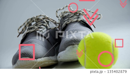 Displaying grey athletic shoes on studio backdrop, with yellow tennis ball and red graphic shapes 135402879