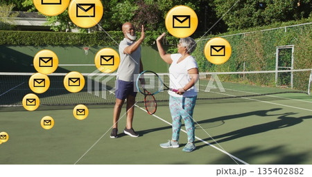 High-fiving man and senior Hispanic woman in tennis clothes at tennis court with envelope icons High-fiving man and senior Hispanic woman in tennis clothes at tennis court with envelope icons 135402882