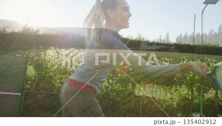 Leaning tennis player in sportswear striking ball on grass court by hedge with racket, copy space 135402912