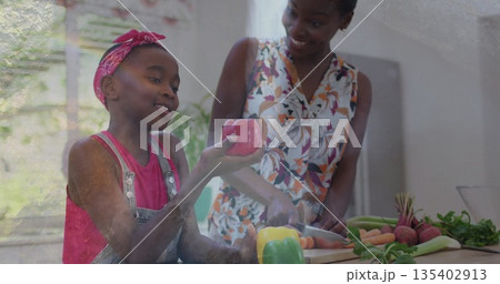 Slicing carrots mom and daughter cooking at home kitchen, with peppers on wooden board, garden view 135402913