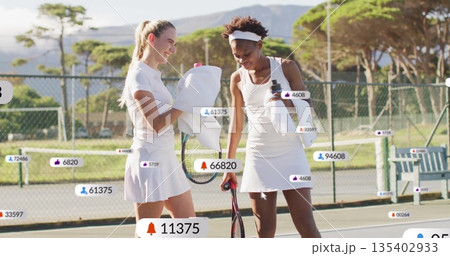 Standing friends in white attire pausing on tennis court, with rackets, bottle, social media icons Standing friends in white attire pausing on tennis court, with rackets, bottle, social media icons 135402933