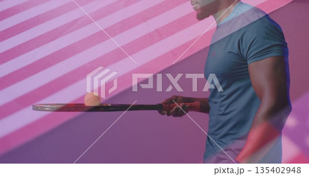 Balancing athlete in blue shirt holding tennis racket with ball in sports studio, copy space 135402948