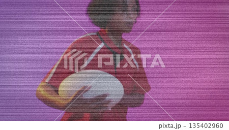 Posing mid adult female athlete holding white rugby ball against solid magenta studio backdrop Posing mid adult female athlete holding white rugby ball against solid magenta studio backdrop 135402960