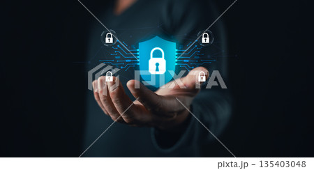 A person holds a glowing digital shield with a padlock icon surrounded by connected locks, symbolizing cybersecurity,data protection,privacy,network safety,and secure technology solutions. 135403048