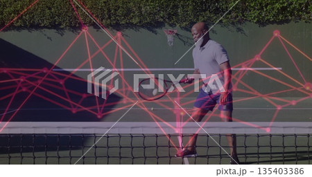 Swinging senior man playing tennis at backyard court with racket, ball, hoop, red network overlay Swinging senior man playing tennis at backyard court with racket, ball, hoop, red network overlay 135403386