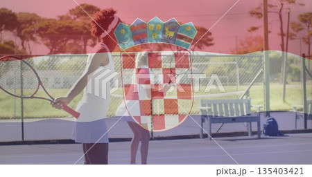 Standing tennis players wearing sportswear holding rackets, facing net on outdoor court, with fence 135403421