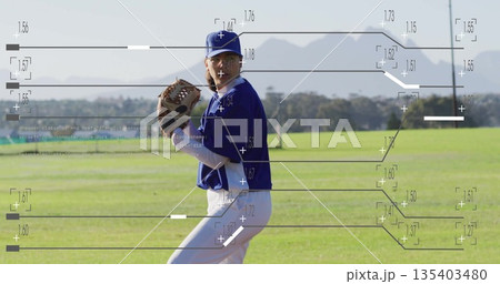 Pitching female player wearing blue uniform and cap on grassy field, with leather glove and ball 135403480