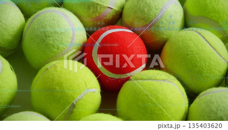 Overlapping yellow-green tennis balls forming contrast on flat surface, with single red tennis ball 135403620