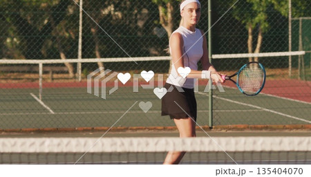 Standing tennis player wearing tennis outfit gripping racket at net on court, with chainlink fence Standing tennis player wearing tennis outfit gripping racket at net on court, with chainlink fence 135404070