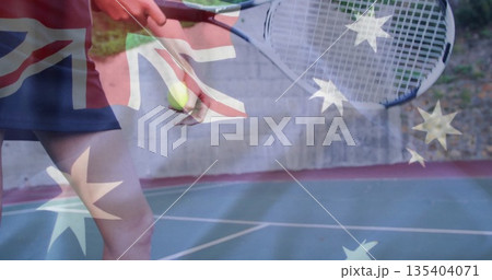 Tennis player in sportswear bouncing ball and holding racket on outdoor tennis court, flag overlay Tennis player in sportswear bouncing ball and holding racket on outdoor tennis court, flag overlay 135404071