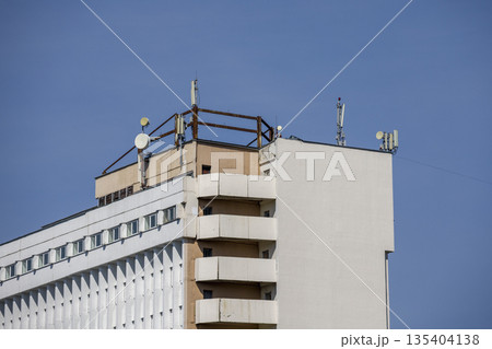 Rooftop features multiple telecommunication antennas placed on a tall building in a city setting in bright daylight 135404138