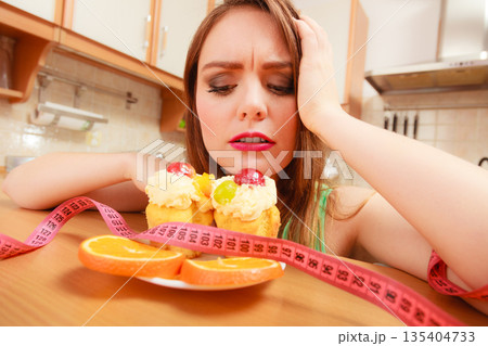 Woman with tape measure and cake. Diet dilemma. Woman with tape measure and cake. Diet dilemma. 135404733