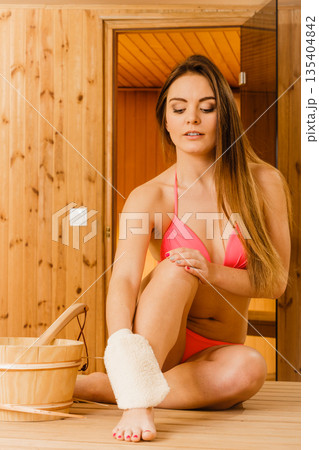 Woman in sauna with exfoliating glove. Skincare. 135404842