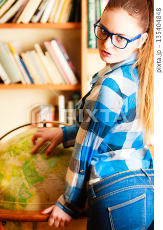 Girl in library pointing to globe Girl in library pointing to globe 135404848