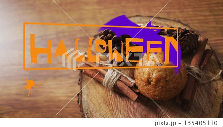 Halloween happy text image over muffin and cinnamon sticks on wooden surface Halloween happy text image over muffin and cinnamon sticks on wooden surface 135405110