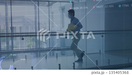 Walking man wearing suit, surgical mask on glass-railed corridor, with yellow folder, copy space 135405368