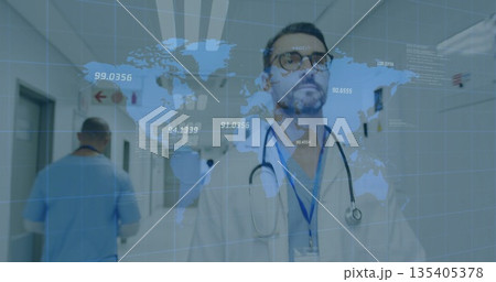 Standing male doctor wearing white coat and stethoscope in hospital hallway, with world map overlay Standing male doctor wearing white coat and stethoscope in hospital hallway, with world map overlay 135405378