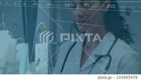 Analyzing doctor reviewing currency codes overlay with graphs in corridor, with stethoscope and pen Analyzing doctor reviewing currency codes overlay with graphs in corridor, with stethoscope and pen 135405478