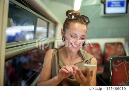 Cheerful Woman Browsing Smartphone on a Train Journey 135406019