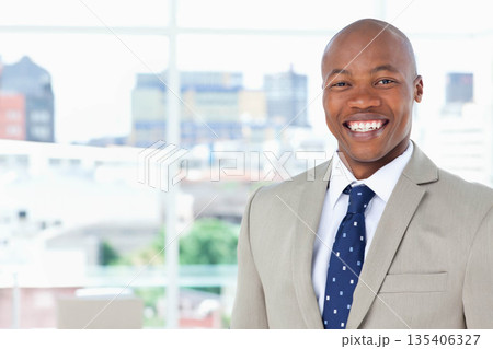 African American man standing before window at office wearing gray suit with navy tie, copy space African American man standing before window at office wearing gray suit with navy tie, copy space 135406327