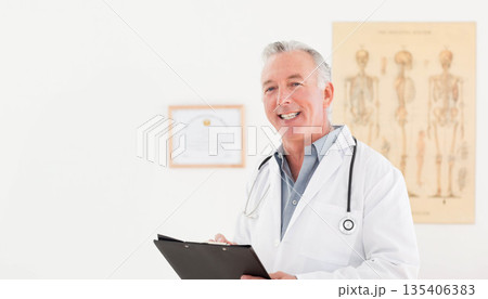 Senior White male doctor holding clipboard and stethoscope in clinic with anatomy chart, copy space 135406383
