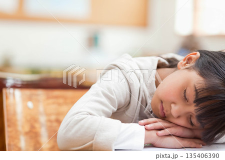 Asian girl student sleeping with folded arms on wooden desk and notebook in classroom copy space 135406390
