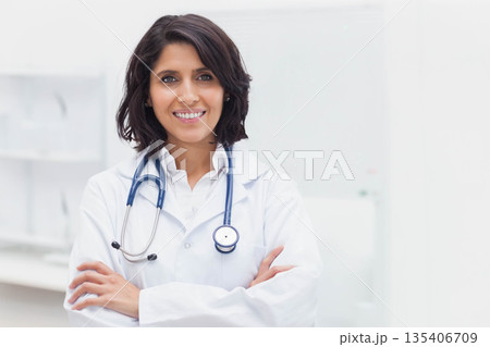 Female doctor standing confidently in bright medical office, wearing lab coat and stethoscope Female doctor standing confidently in bright medical office, wearing lab coat and stethoscope 135406709