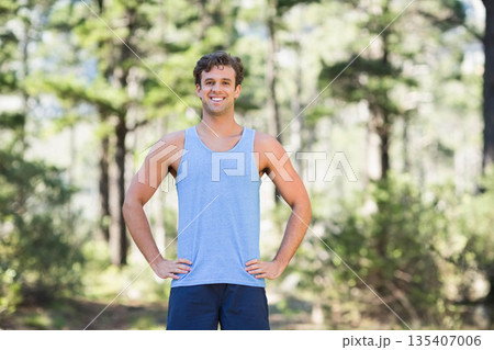 Man running on forest trail in blue sleeveless shirt and navy shorts under sunlit pine canopy Man running on forest trail in blue sleeveless shirt and navy shorts under sunlit pine canopy 135407006