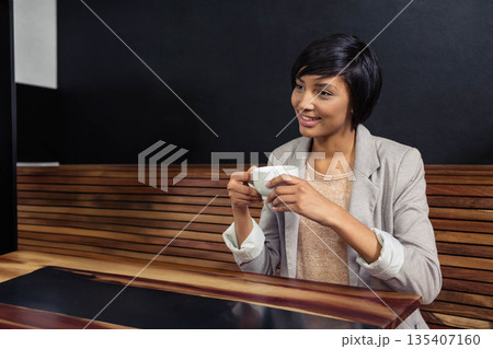 Asian woman holding white ceramic coffee cup at wooden bench table in modern café, copy space Asian woman holding white ceramic coffee cup at wooden bench table in modern café, copy space 135407160