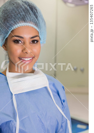 African American woman standing in OR pulling mask down while wearing scrubs under overhead light 135407265