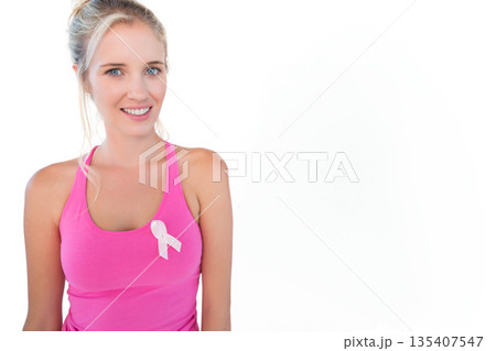 Woman wearing pink top facing white backdrop and showing pale pink awareness ribbon, copy space Woman wearing pink top facing white backdrop and showing pale pink awareness ribbon, copy space 135407547