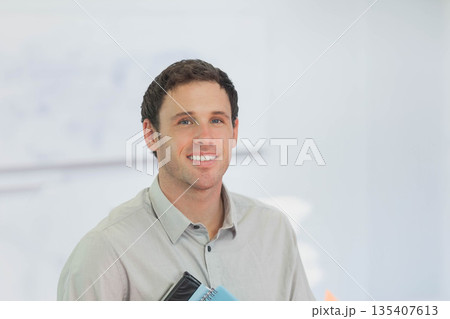 Man in his thirties wearing gray shirt holding notebooks and folders in bright office, copy space Man in his thirties wearing gray shirt holding notebooks and folders in bright office, copy space 135407613