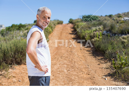 Senior man standing hands on hips on red dirt hiking trail on rocky hillside, copy space Senior man standing hands on hips on red dirt hiking trail on rocky hillside, copy space 135407690