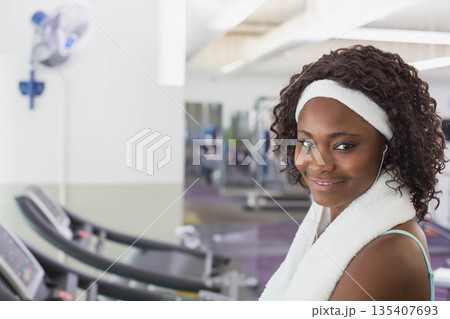 African American woman standing next to treadmill in gym with towel and earphones, copy space 135407693
